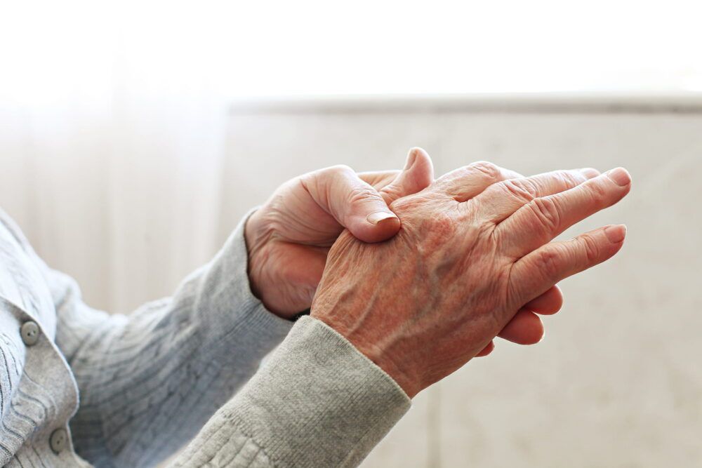 Elderly woman applying moisturizing lotion cream on hand palm, easing aches. Senior old lady experiencing severe arthritis rheumatics pains, massaging, warming up arm. Close up, copy space,