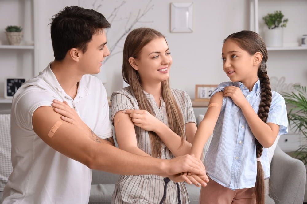 Family with medical patches after vaccination putting hands together at home