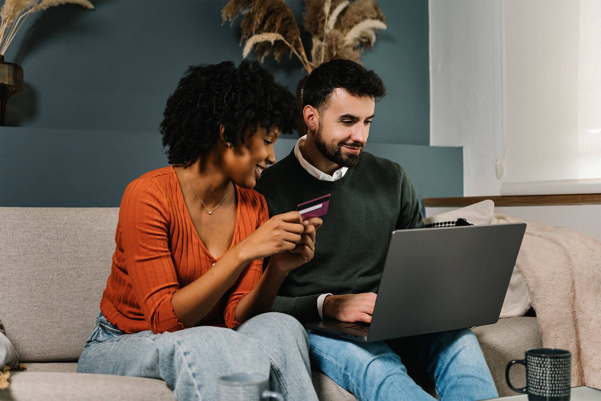 Young cheerful couple shopping at home with credit card and laptop, buying on online retail shop