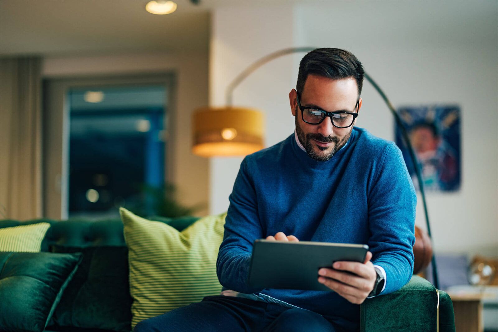 Positive businessman using a digital tablet while sitting on the couch.