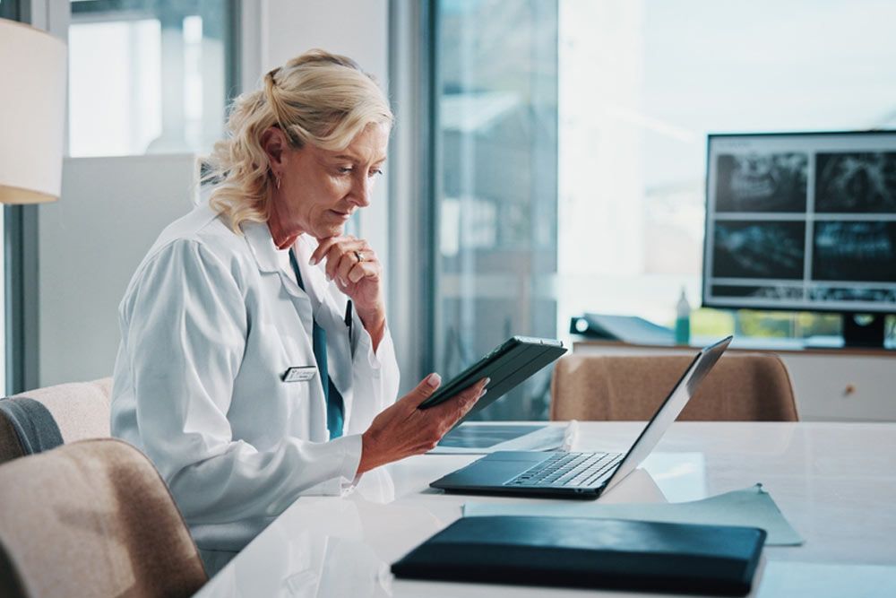 Doctor, healthcare and technology with woman at office desk in hospital for diagnosis, planning or research.