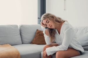 Depressed or tired teen girl feeling stress headache hurt pain sitting alone at home, upset sad heartbroken