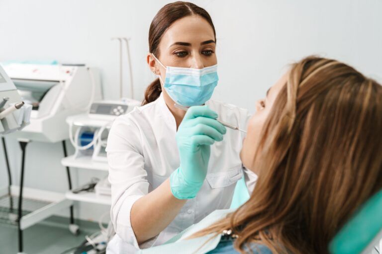European mid dentist woman in face mask working in dental clinic