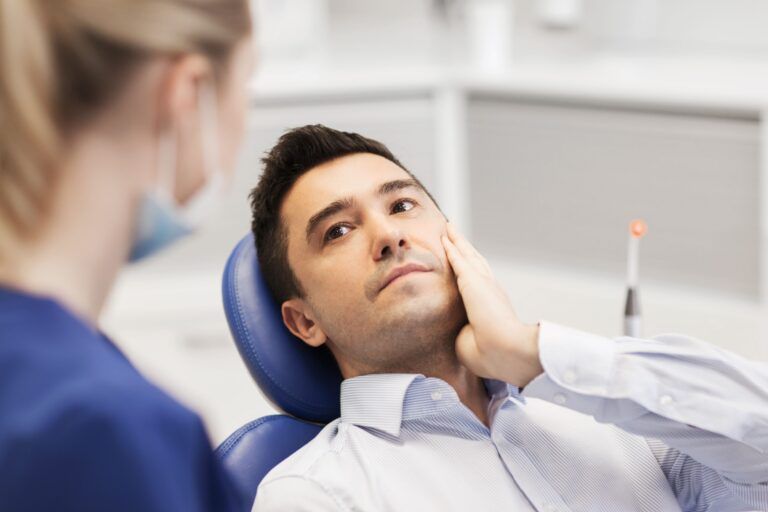 people, medicine, stomatology and health care concept - male patient with toothache complaining to female dentist at dental clinic office