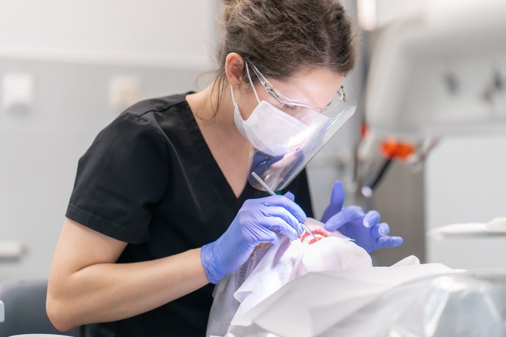 The dentist examines the patient's mouth and teeth using a dental explorer