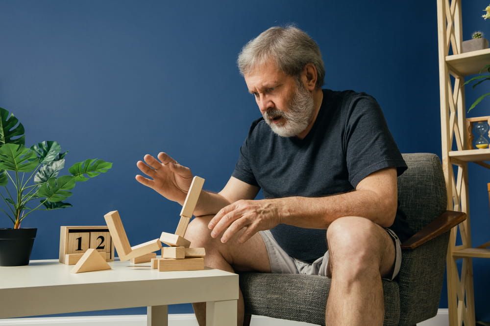 Old bearded man with alzheimer desease has problems with his hands motor skills. Illness, memory loss due to dementia, healthcare, neurological disorder, sadness concept.