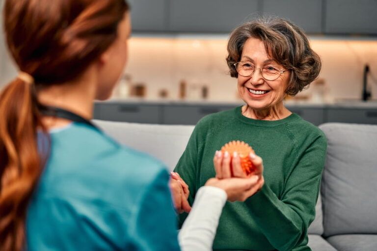 Smiling senior woman holding a spiked ball in her hand for rehabilitation and recovery of arm muscles after illness