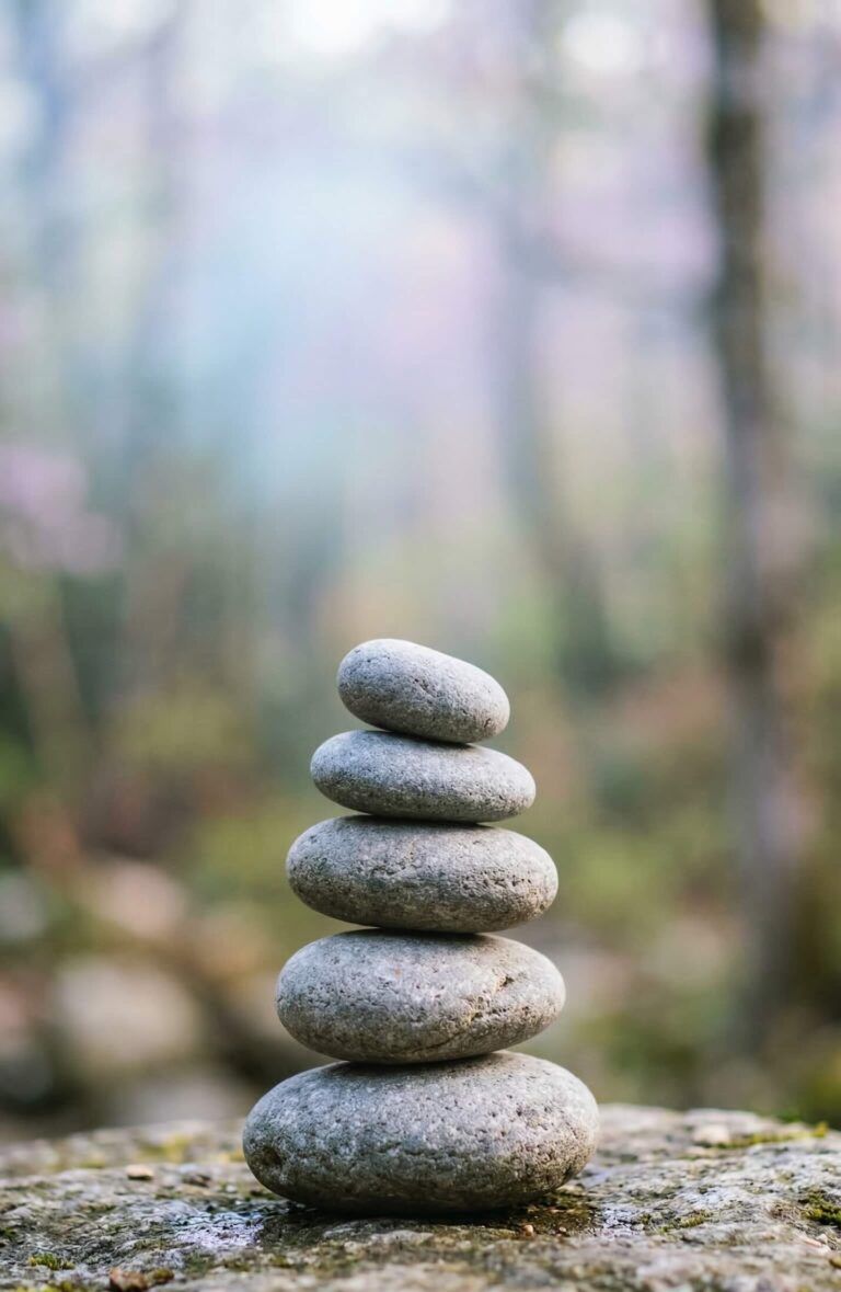 Minimal stacked stones in soft natural light with blurred nature background, calm and serene mood
